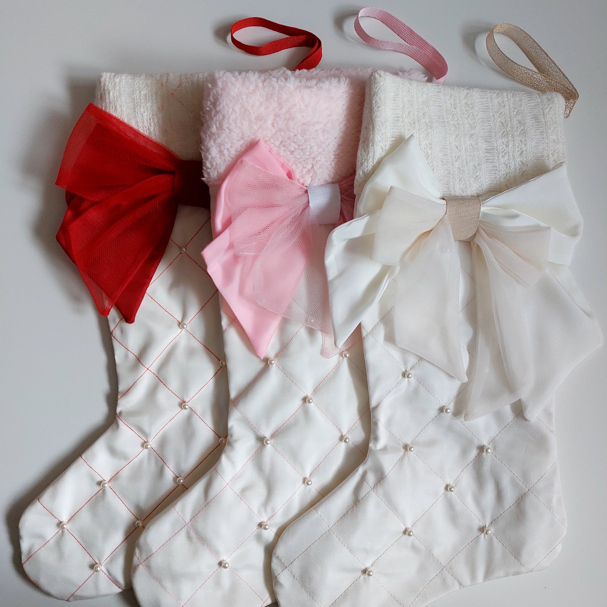 Three decorative stockings with large bows in red, pink, and white 