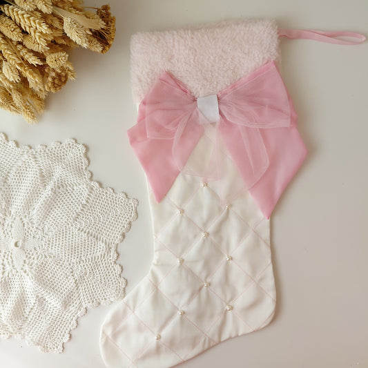 White textured stocking with a pink bow on a light surface with decorative elements.