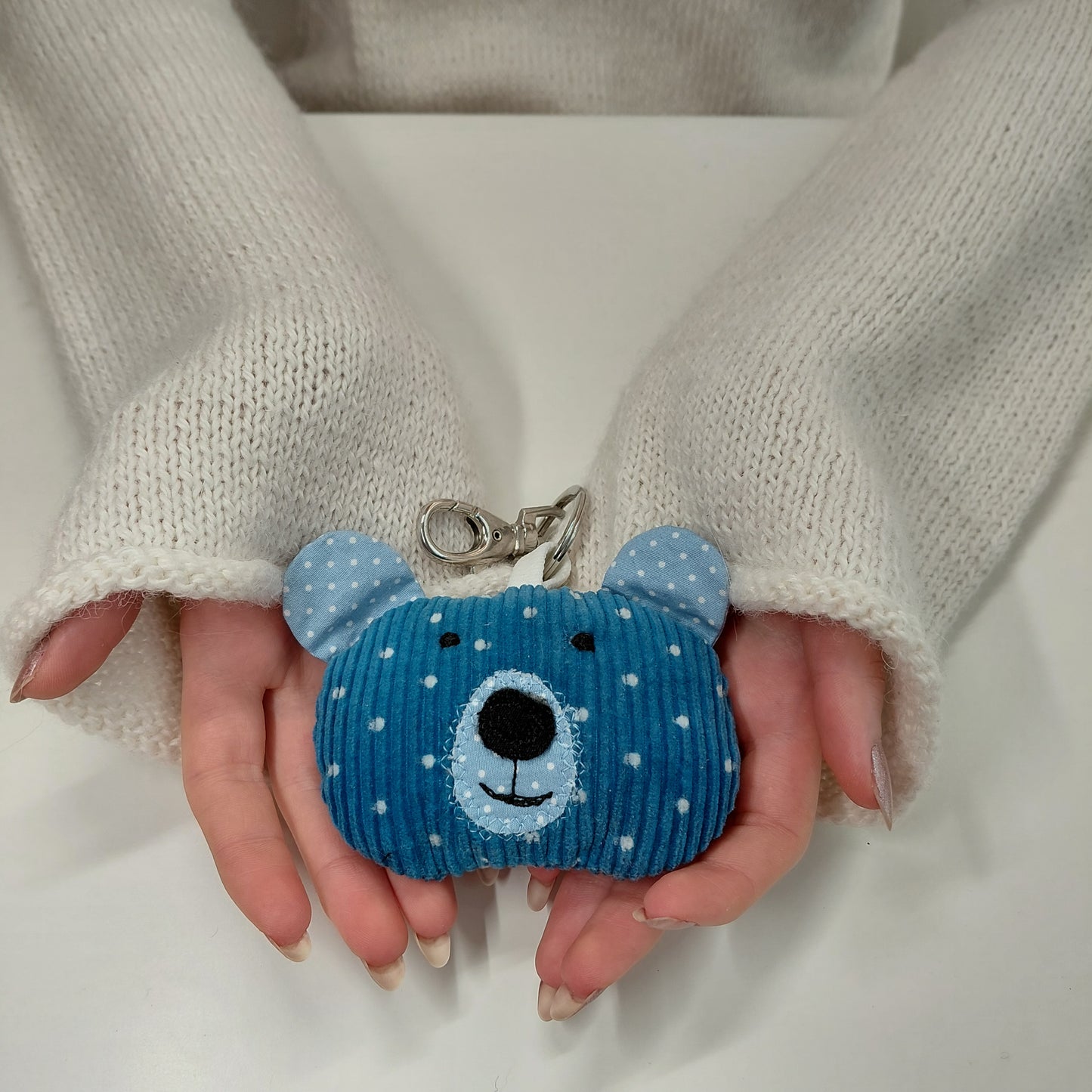 Blue bear-shaped keychain held between two hands